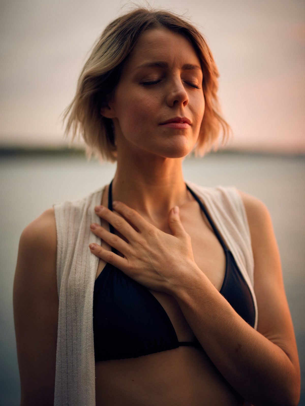 A woman with her eyes closed and a hand on her chest, breathing mindfully