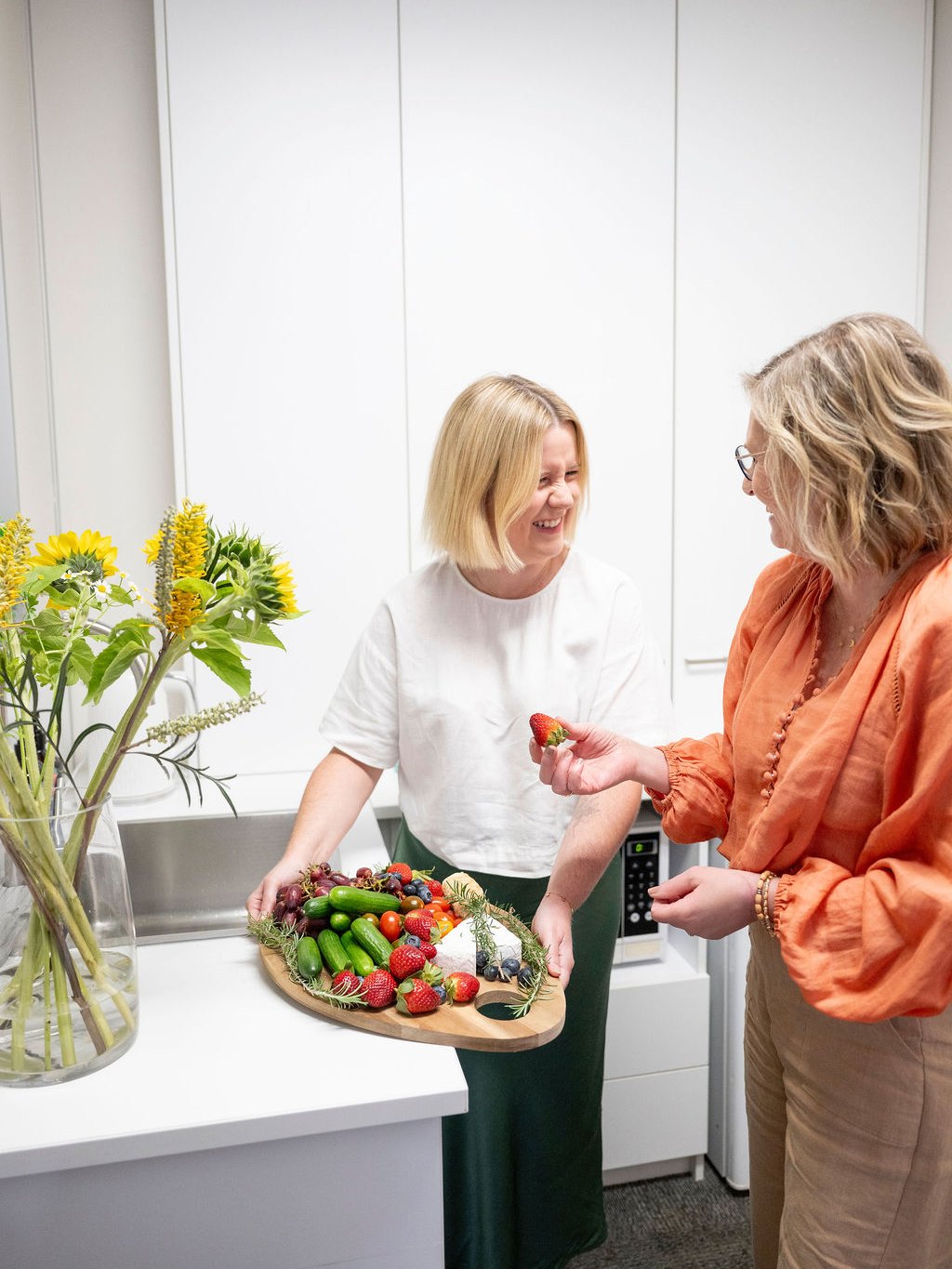 Two team members sharing a platter of fresh fruit and vegetables