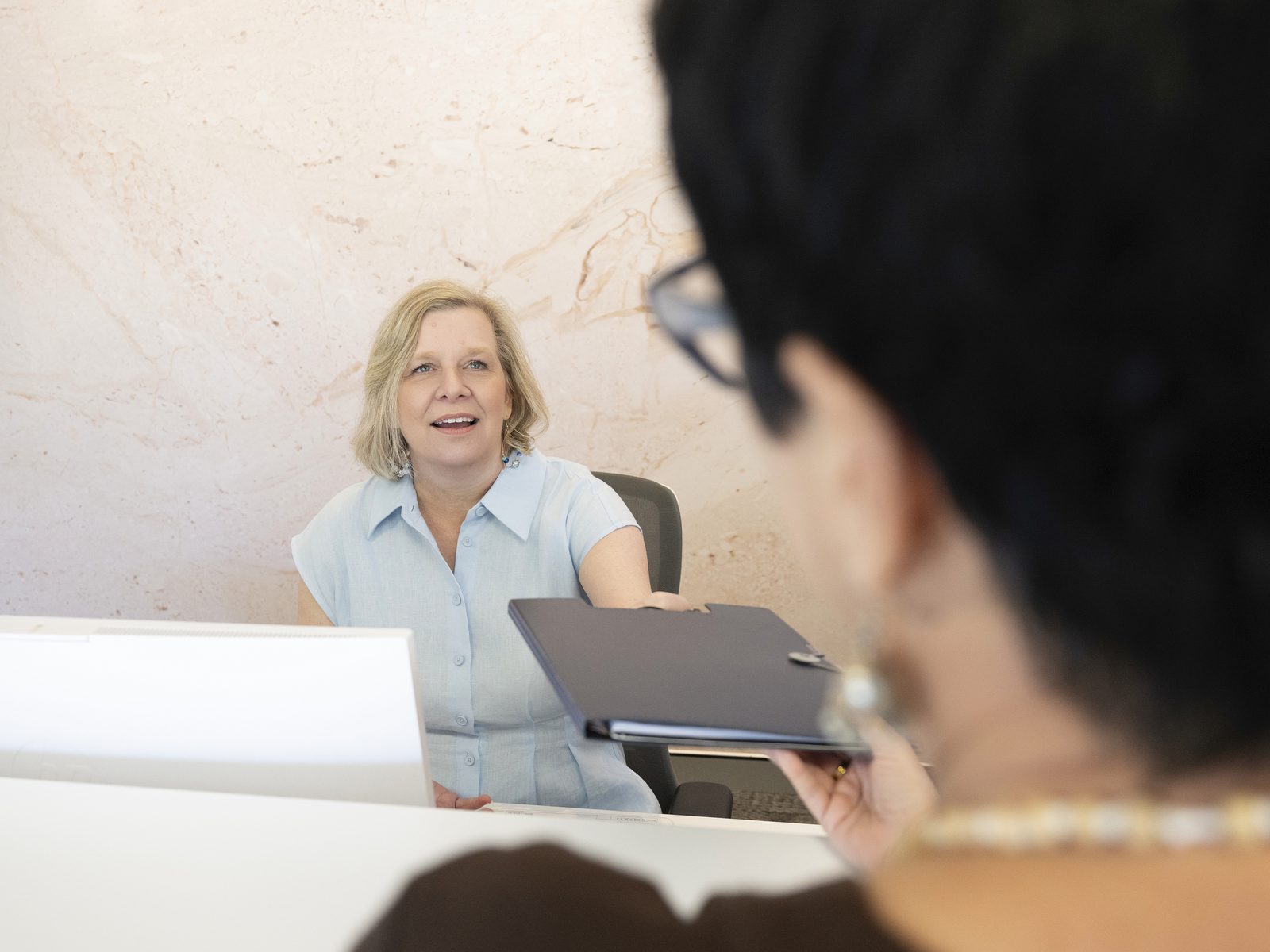 A receptionist greeting a client at the front desk