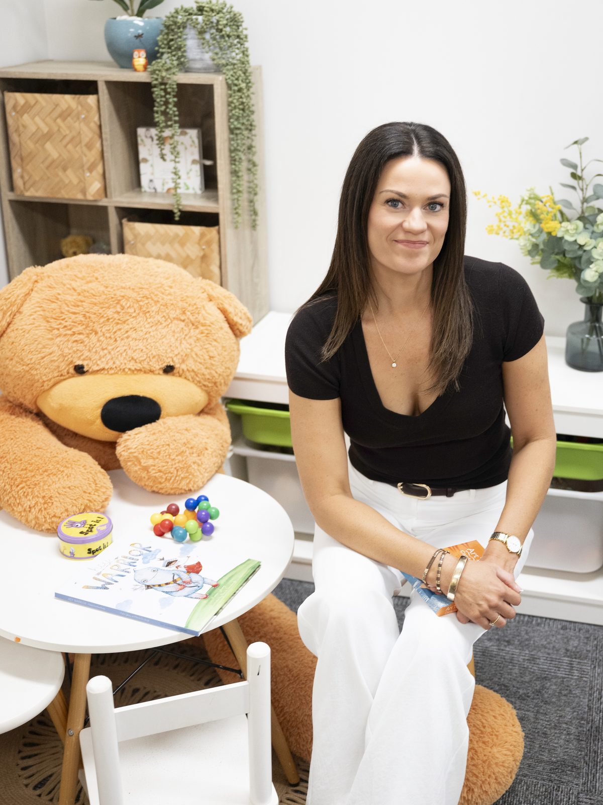 A practitioner seated in the children's therapy corner beside the giant teddy bear