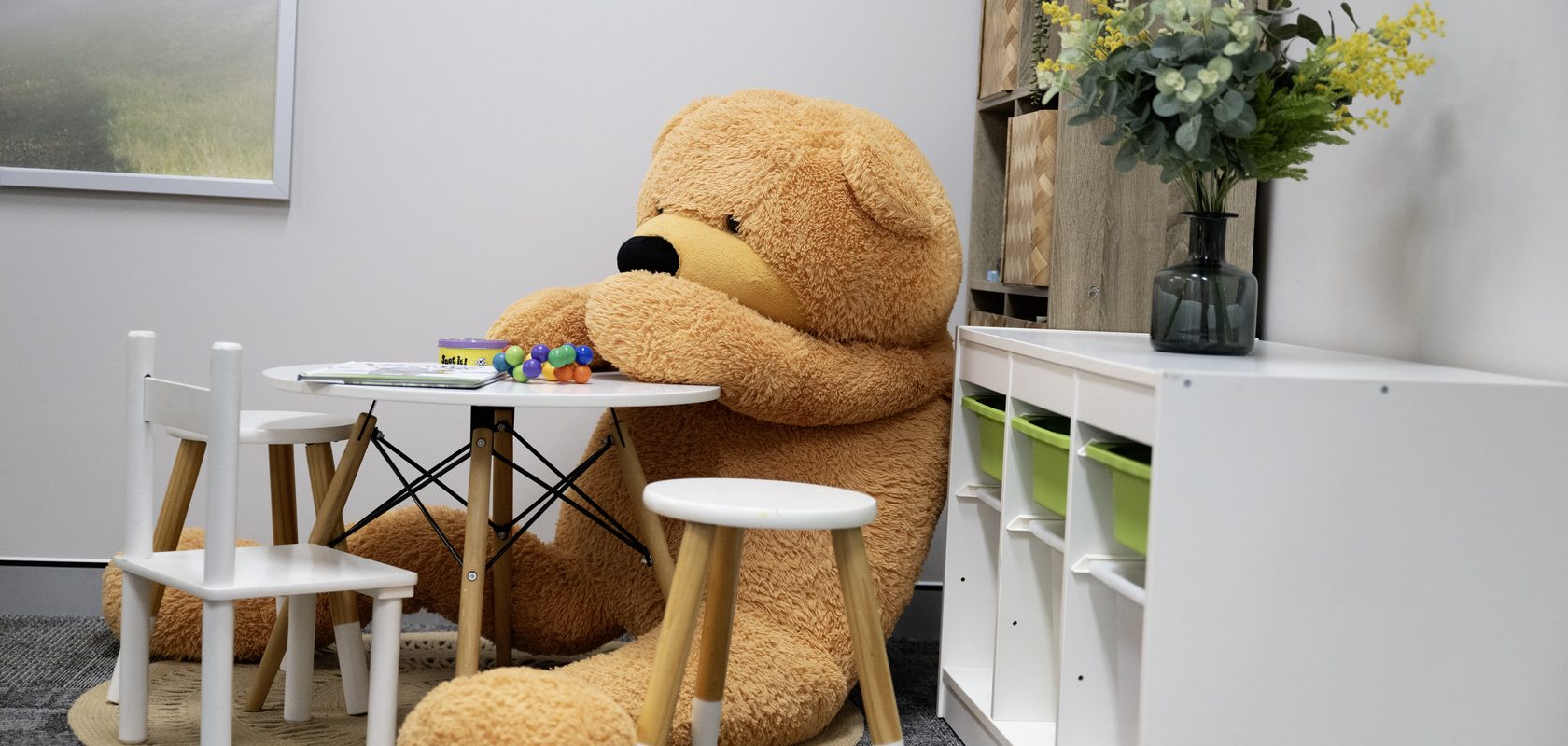 The children's corner with a giant teddy bear seated at a small white table