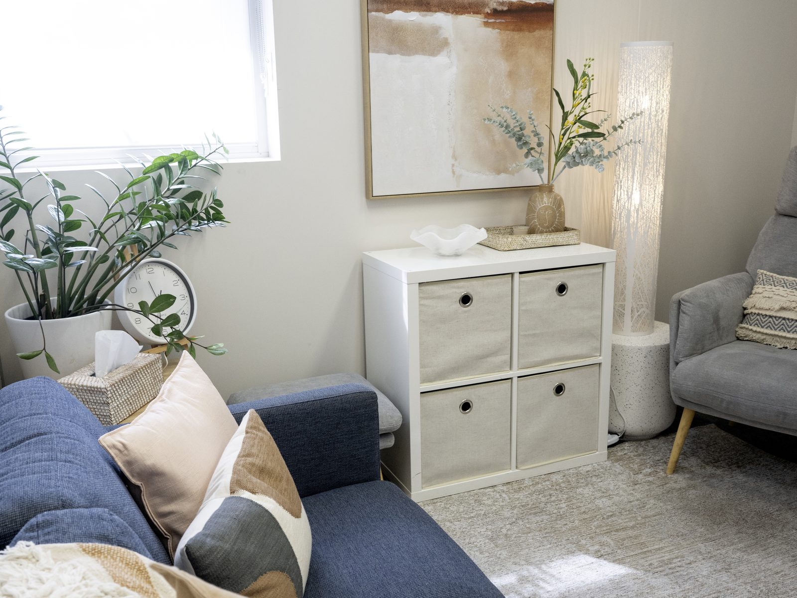 A navy sofa with blush and cream cushions beside white storage cubes