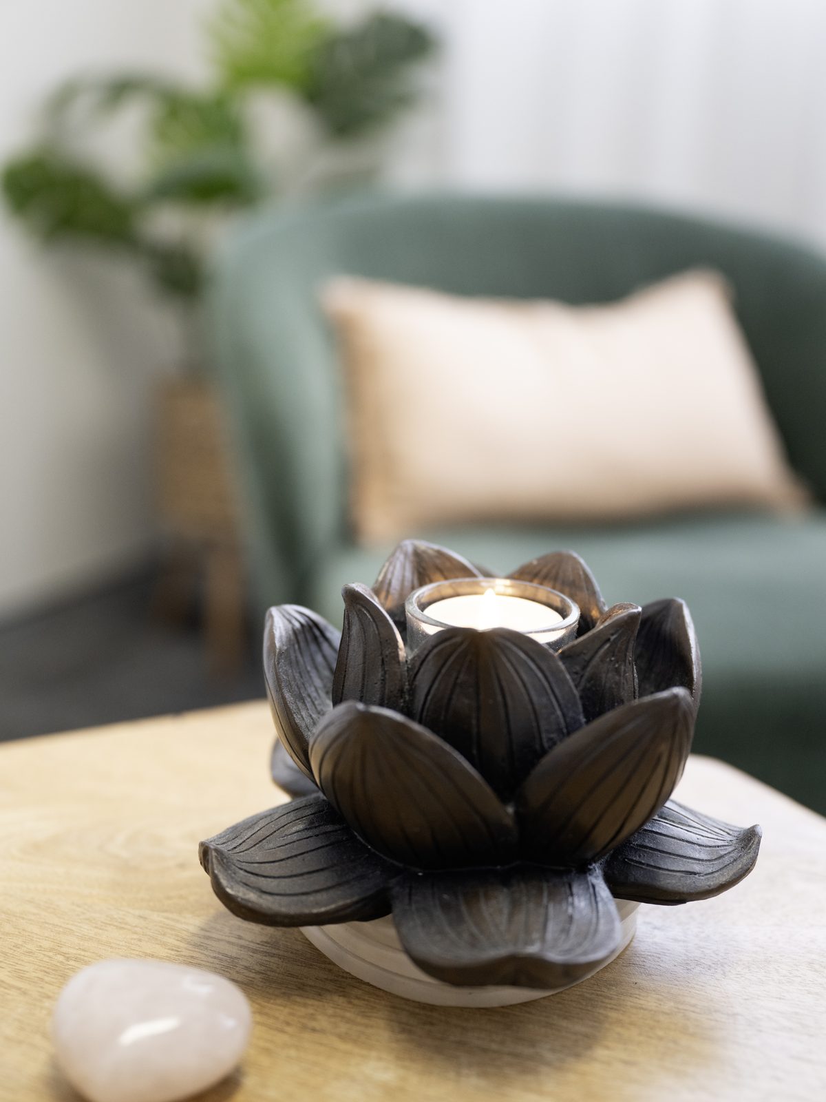 A lotus-shaped candle holder and a rose quartz heart on a timber coffee table